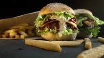 Big homemade appetizing burgers with toasted buns served with crispy french fries. Fast food, unhealthy eating habits