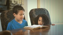 a brother and sister reading a Bible