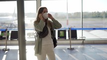 Female traveller putting on protective mask standing at the airport.
