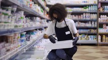 Female worker arranging products on shelves in milk department in supermarket.