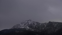Mountain massif covered with snow. Windy winter weather. Clouds and fog, timelapse