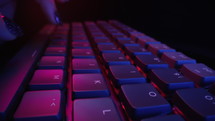 Super macro dolly of woman typing on computer RGB keyboard buttons in neon light. Working at night. Cybersportswoman. High quality 4k footage