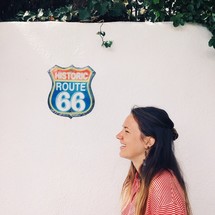 A smiling woman next to a wall with a Route 66 sign.