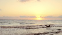 Sea waves splashing sand seashore at cold morning sunrise.