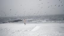 Girl chasing seagulls on the shore during winter