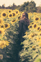 Girl walking through a field of sunflowers