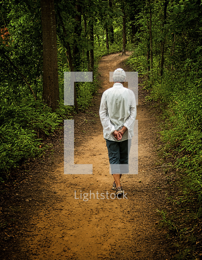 Woman walking on a dirt path lined with trees.