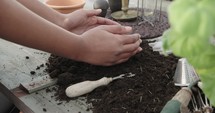 a woman putting potting soil into clay pots 