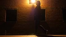 a woman walking alone outdoors at night 