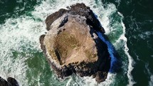 drone flying over a rock formation in the ocean 