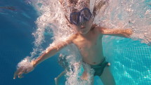 Happy little boy jumping in pool blue clear water, fun for children. Summer swim, underwater leisure. Funny kid, enjoy diving. Extreme angle. High quality 4k footage