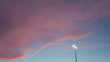 Line of airplane exhaust in pink and blue sky at dusk.