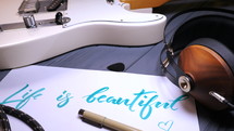 Life is beautiful hand lettering near headphones and guitar