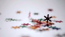 Falling on white table decoration colorful snowflakes. New Year or Christmas holiday concept. Slow motion.
