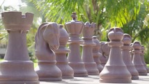 Tracking shot of ivory chess pieces on a marble chess board
