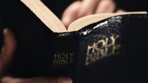 Upclose shot of a man reading and flipping through the Holy Bible.