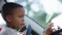 Curious cute preschool kid boy using digital touchscreen technology inside a car panel. Children tech addiction concept
