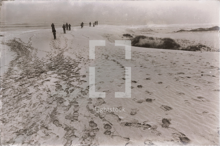 people walking on a beach leaving footprints in the sand 