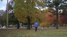 grandfather chasing his granddaughter in a park 