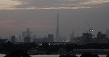 Distant Dubai skyline with Burj Khalifa and other skyscrapers and buidings as the sun sets.
