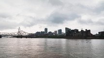Going up the Mississippi River to Saint Louis, Missouri skyline with buildings and the arch on a cloudy day.