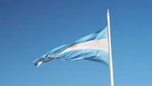 The Flag of Argentina waving in the wind against a blue sky.
