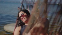 Young woman enjoying the sun and swinging in a hammock while relaxing on her vacation.
