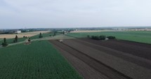 Aerial drone shot of Farmer Tilling Soil At a Farm Field With Agricultural Tractor. 