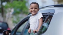 Little kid looking out car window. Summer trip with family. Happy boy excited to travel with family. Dream kid. Happy family traveling by car. Smile of kid in car window
