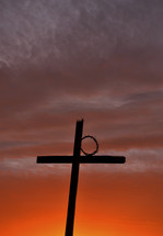 silhouette of a cross and a crow of thorns against a fiery sky at sunset 