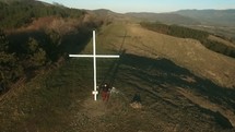 man standing next to a cross on a mountaintop 