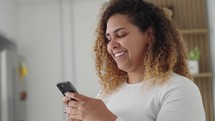 Happy black woman holding cell phone using smartphone device at home. 