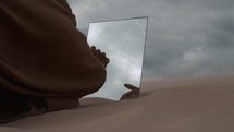 Man touches mirror in the desert