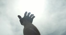 Bright light shines on hand of man raising his hand worshipping. Young man in worship, prayer and faith.