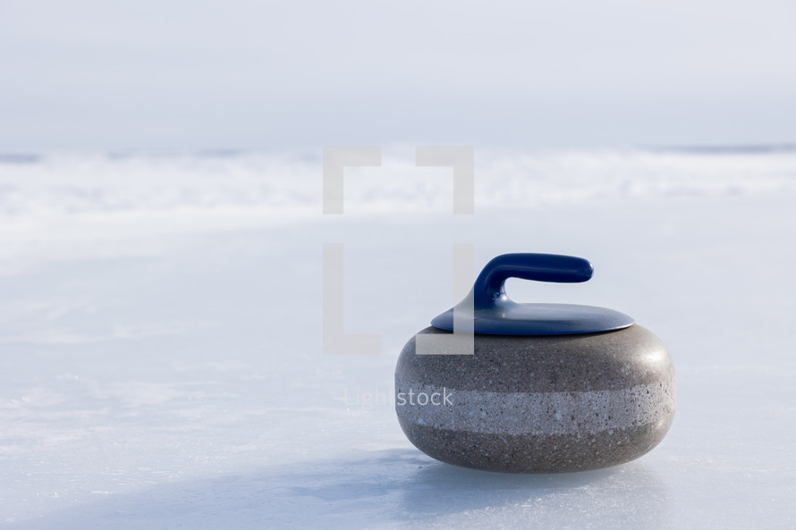 One blue curling rock on a frozen lake