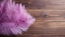 Purple feathers on wooden background. Top view with copy space.