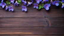 Purple flowers on brown wooden background. Top view with copy space