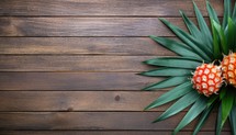 Pineapple and palm leaves on wooden background. Top view with copy space