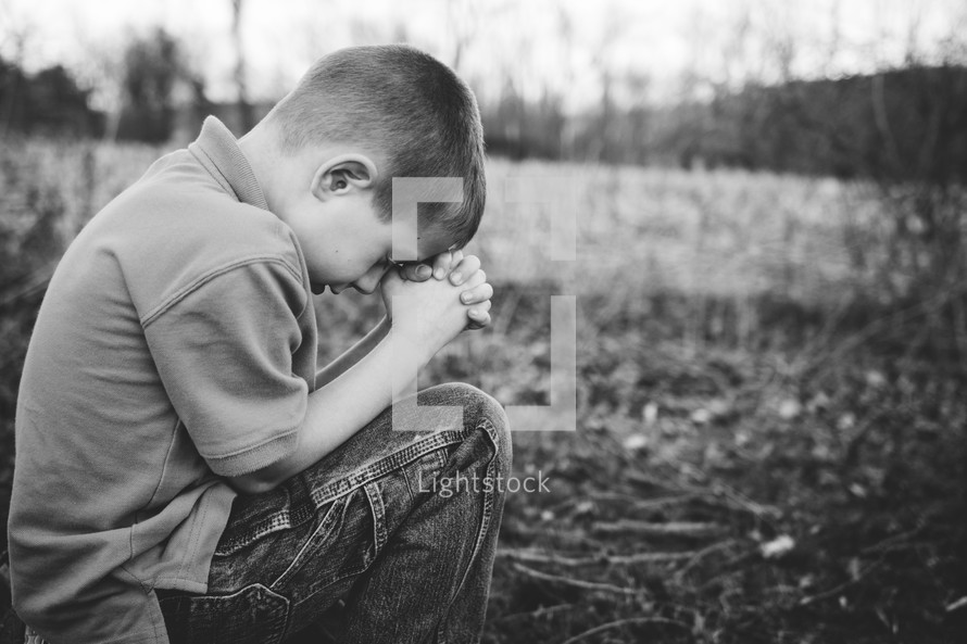 boy child with head bowed in prayer 