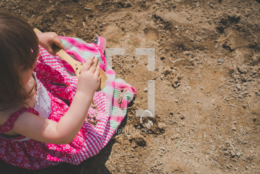 a little girl playing in dirt 