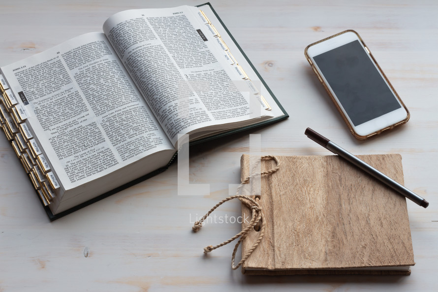 phone, Bible and journal on a white wood background 