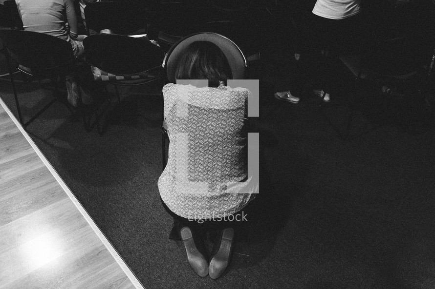 woman kneeling in prayer over a chair 