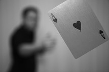 a man throwing an Ace of spades playing card 