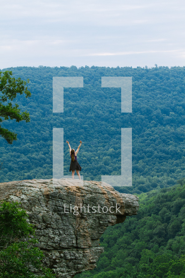 woman standing with raised arms on a mountaintop 