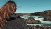 a woman looking out at a waterfall in Iceland 