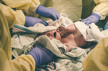 Newborn baby being cleaned by hospital staff.