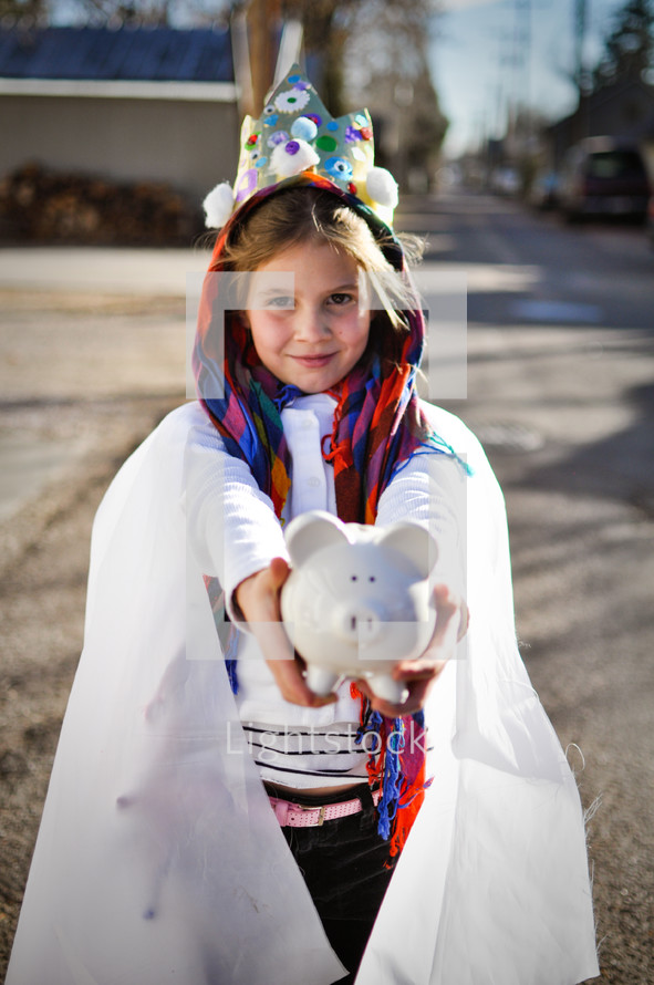 a child in a live nativity scene holding a piggy bank 