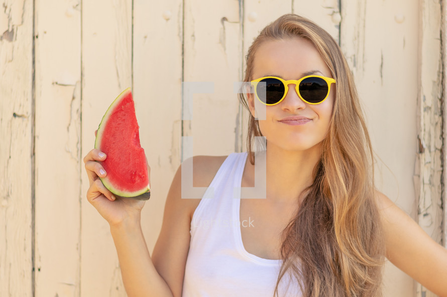a teen girl holding a watermelon slice 