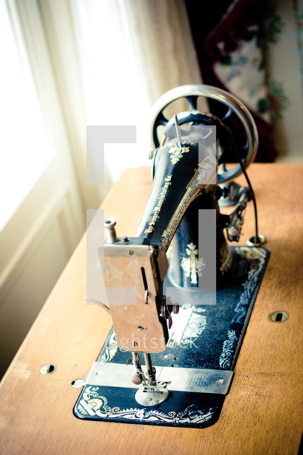 Anique sewing machine on wooden sewing table.