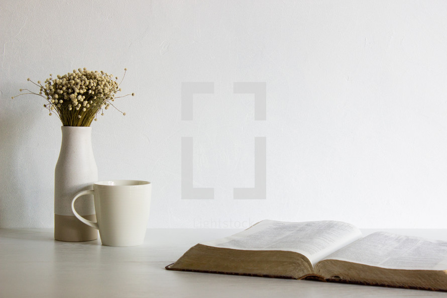 open Bible, vase, and coffee cup 